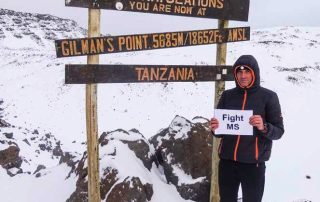 Martin Geicsnek am Kraterrand des Kilimandscharo mit der Botschaft „Fight MS“